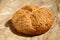 Close up of a fresh, whole wheat small roll bread with sesame seeds on a brown unbleached baking paper