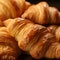 Close-up of freshly baked tasty croissants as background, placed in rows on a black tray. Food concept. Warm Fresh Buttery