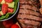 Close up freshly grilled bone steak on wood and fresh salad in bowl