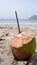 Close up of freshly harvested and prepared green coconut drink on a tropical beach