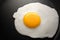 Close up fried egg on frying black pan.
