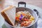 Close-up of fried eggs with bacon, hotdog, fresh tomato, and bread on a pan. Breakfast set