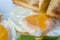Close up of fried eggs, green beans with piece of toast on white plate. English breakfast.