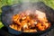 Close-up of fried pieces of pork ribs in a black cast-iron cauldron. Food in nature. Small depth of field