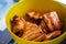 Close-up of fried pieces of pork ribs in a yellow plastic bowl. Food in nature. Small depth of field