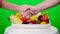 Close-up, friendly handshake on Chromakey, green background and a box full of different vegetables, in studio. concept