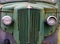 Close up of the front of an old abandoned rusting green truck covered in moss