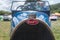 A close up of the front of an old Bugatti car with its red emblem with two older gentlemen admiring the car in the