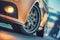 Close-up of front sports car wheel on the asphalt road at dusk cold light