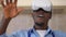 Close-up front view carefree African American man in VR headset gaming online standing in kitchen. Portrait of happy