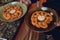 Close up front view of a fried bread coated shrimp, selective focus on single piece in chopsticks, with fresh garnishes.