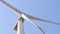 Close - up of a front of a white rotor of a wind generator with a clear blue sky on the background.