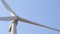 Close - up of a front of a white rotor of a wind generator with a clear blue sky on the background.