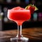 Close up of frozen strawberry margarita garnished with a salt rim and a lime slice in restaurant. Margarita with crushed ice. Red