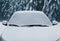 Close up frozen winter car covered snow, view front window windshield and hood on snowy forest