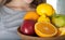 Close up of fruits in wooden bowl. Healthy. Kiwi, Lemon, orange, apples composed in wooden bowl and held by young woman.