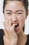 Close-up of frustrated Chinese woman over white background