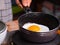Close-up of frying tasty fried egg in a hot pan. Female hand breaks chicken egg falls into the kitchen pan. Concept of Nutritious