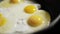 Close up of frying tasty fried eggs in hot pan. Cooking process. Concept of nutritious family breakfast.