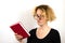 Close-up of a funny girl student with glasses and a strange hairstyle, a mess on her head, holding a book in her hands