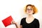 Close-up of a funny girl student with glasses and a strange hairstyle, a mess on her head, holding a book in her hands