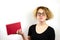 Close-up of a funny girl student with glasses and a strange hairstyle, a mess on her head, holding a book in her hands