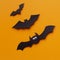 Close up of funny Halloween bats flying up on orange