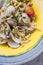 Close up Fusilli Avellinesi pasta with clams and tomato in yellow and blue plate