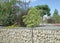 Close-up of a gabion support wall with wire mesh reinforcement and pebbles