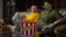 Close-up game controller and popcorn on table with blurred men sitting down on sofa at background. Unrecognizable