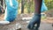Close-up of garbage in forest and hands in gloves collecting trash in bin bags