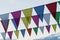 Close-up garland of colorful flags of triangular shape, pennants against blue sky. City street holiday. Modern