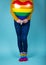 Close-up of gay woman holding a rainbow colored balloon with matching socks on blue background. Valentines day concept