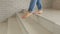 Close-up of a girl with bare feet in ripped jeans coming down the stairs at home