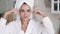 Close up of girl in bathrobe, with towel on head does rejuvenating facial massage