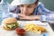 Close-up of a girl in a cap and shirt, sitting at a table and looking at food, fast food, Burger and fries