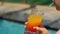 Close-up of a girl drinking a cocktail of straw sitting on the edge of the pool.
