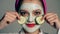 Close up girl face with mask that closes her eyes with cucumbers on a gray background. Face care concept. Beautiful girl
