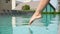 Close-up. The girl gently slowly touches the water in the pool with her foot. Relax concept