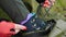 Close-up of a girl hiker's hand in red gloves and red manicure tying the laces on her boots. The concept of mountain