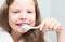 Close-up, a girl with long hair, brushing her teeth with a brush and paste