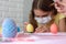 Close-up of a girl in a medical mask who paints Easter eggs