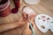 Close-up of girl painting clay mug. Woman coloring pottery in workshop with a paintbrush. Painter in white tanktop