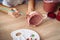 Close-up of girl painting clay mug. Woman coloring pottery in workshop with a paintbrush. Painter in white tanktop