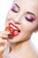 Close up of girl with red lips eating strawberry