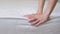 Close up of a girl's hand checks the rigidity of a new comfortable orthopedic white mattress for the bed. Female