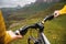 A close-up of the girl`s hand cyclist on the handlebars of a mountain bike against the backdrop of epic rocks and