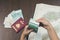 Close-up of girl`s hands counting a bundle of Malaysian money.A map of Malaysia and travel passport on the background