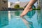 Close-up of a girl`s leg descends into the pool. The foot touches the water. Checks the water temperature before swimming