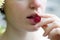 Close up of girl`s mouth eating raspberry